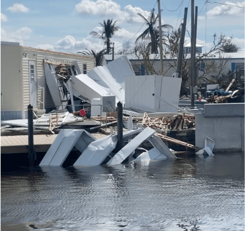 Storm damaged waterfront canal with broken dock pieces and debris in the water