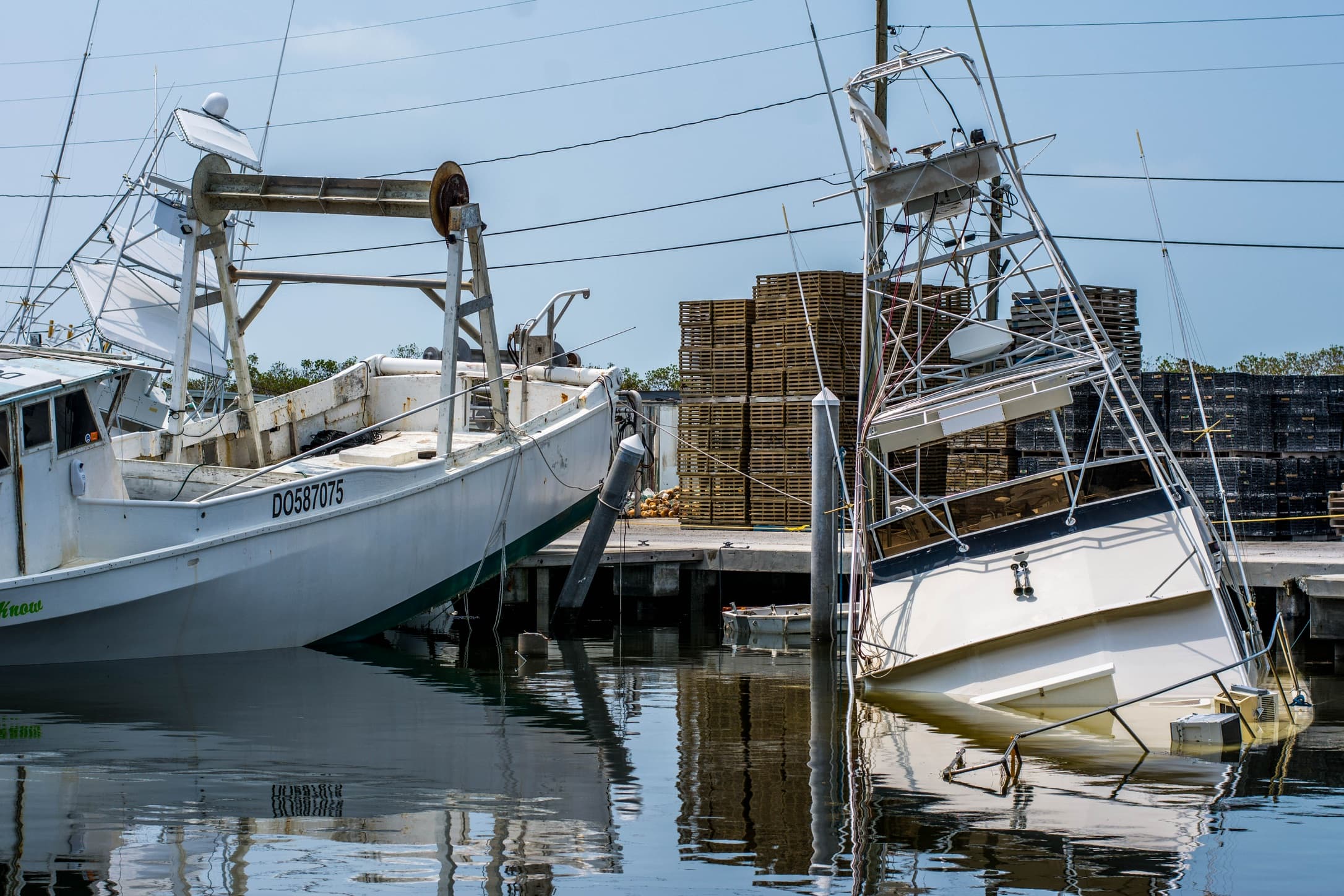 Storm surge damaged boats leaning against a marina dock after coastal flooding
