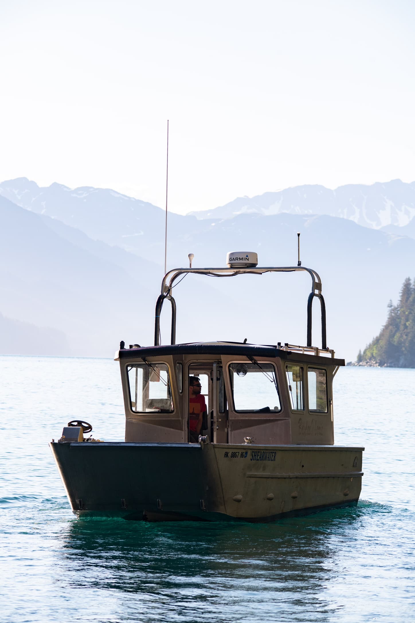 Small cabin boat on calm water with mountains behind it