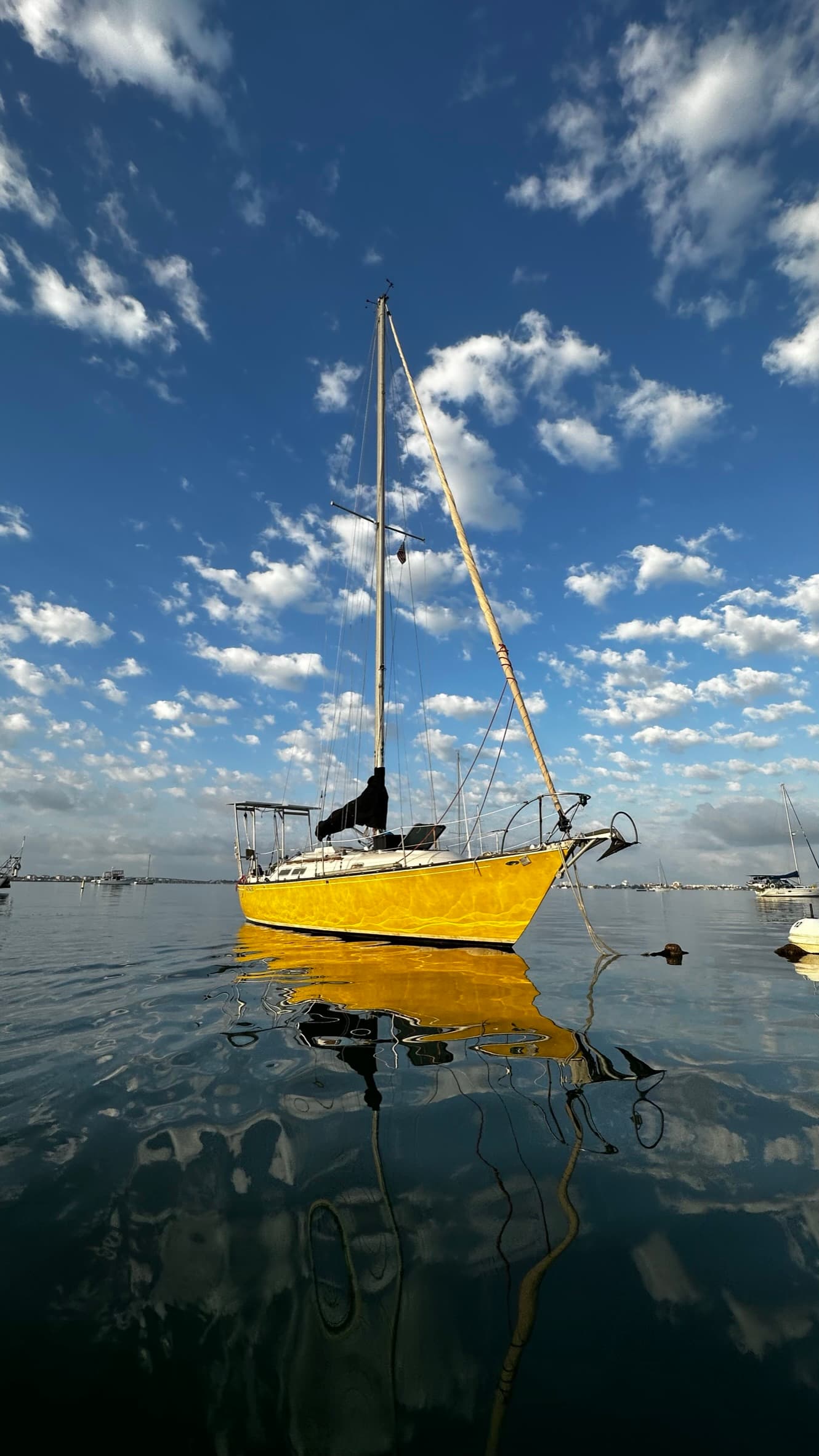 Yellow sailboat resting on calm water under a blue sky