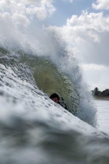 Surfer tucked inside a translucent breaking wave