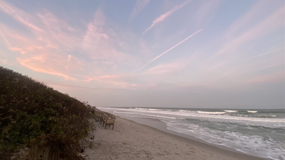 Pink dawn clouds over a Florida beach before sunrise