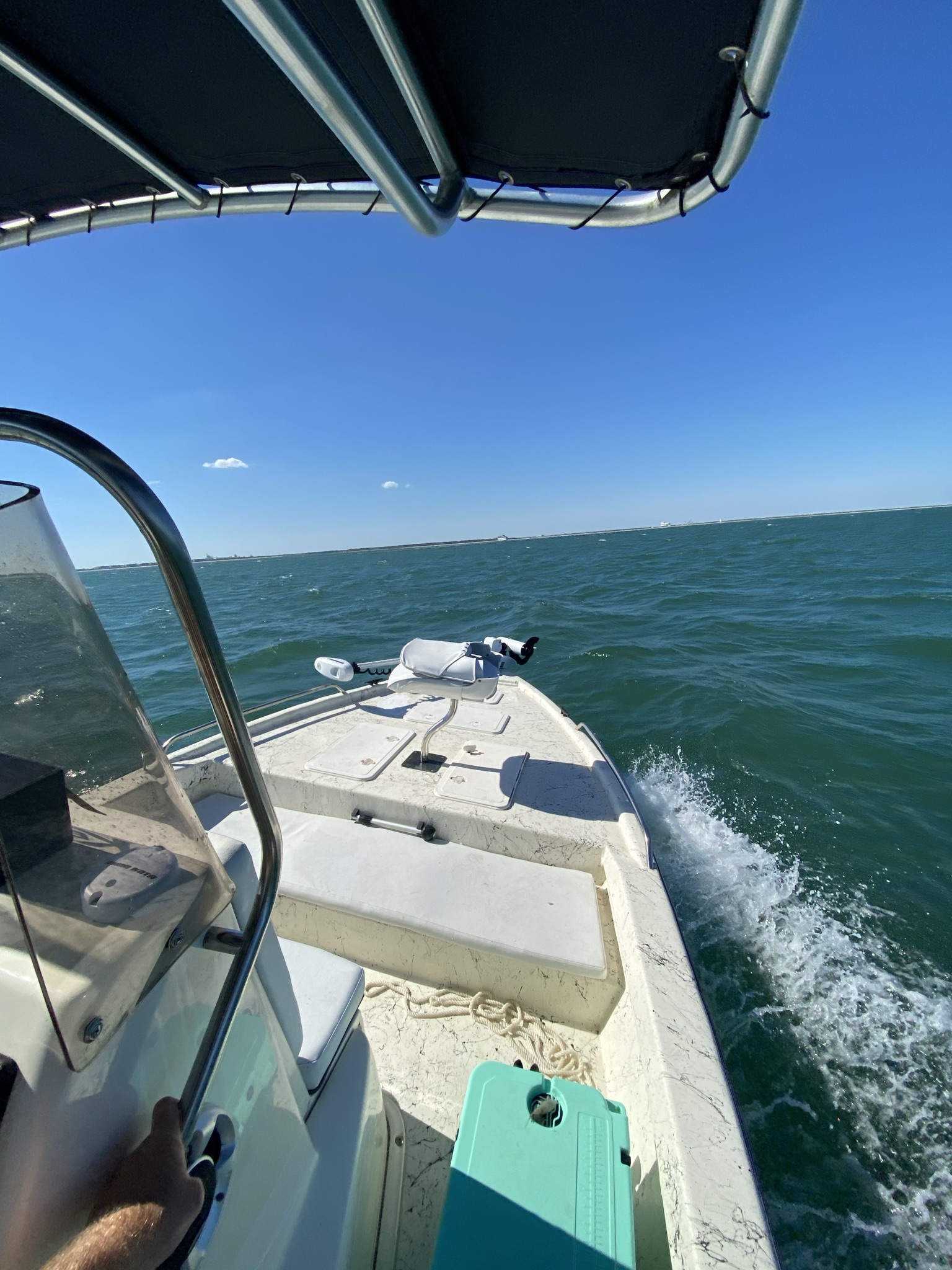 Small boat running across green Gulf Coast water under a blue sky